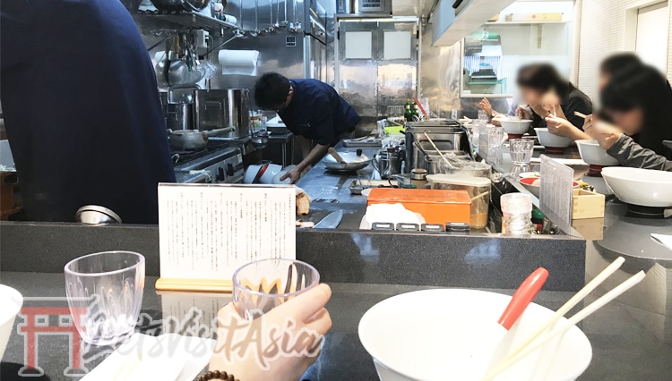 An image of us sat down inside Tsuta after finishing our bowl of ramen, with the kitchen and chefs viewable.