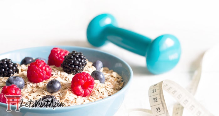 A bowl of oats with some berries on top with a dumbbell 